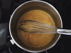 turmeric golden milk with a whisk in saucepan