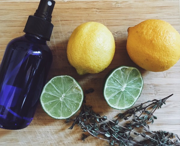 Lemons, limes and thyme on wood cutting board with spray bottle