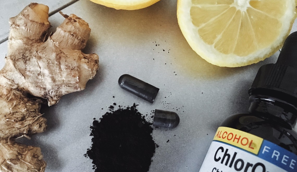 Ginger root, lemon, activated charcoal and liquid chlorophyll bottle on counter