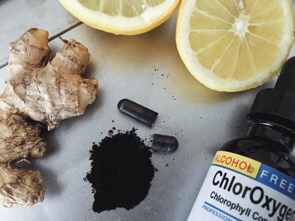 Ginger root, lemon, activated charcoal and liquid chlorophyll bottle on counter