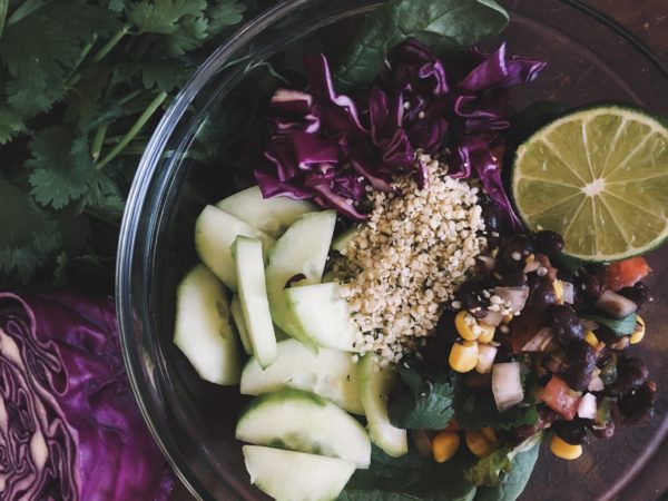 Organic salad in a bowl with cucumber, purple cabbage, hemp seeds, lime and black bean salsa